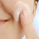 caucasian smiling woman applies moisturizer onto face